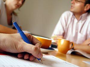 méthode Main tenant un stylo avec deux personnes parlants en arrière plan